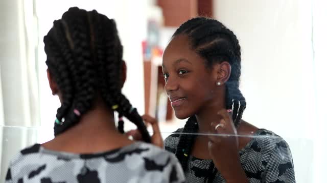 十几岁的黑人女孩看着镜子里的自己。青春期的非洲女孩检查脸视频素材