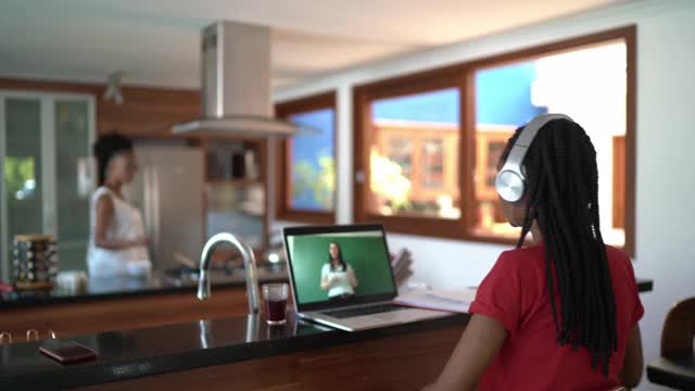 十几岁的女孩在厨房用笔记本电脑看课，父亲在家里给她端吃的视频素材