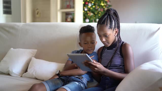 兄弟姐妹在家里用平板电脑或电子阅读器阅读视频下载