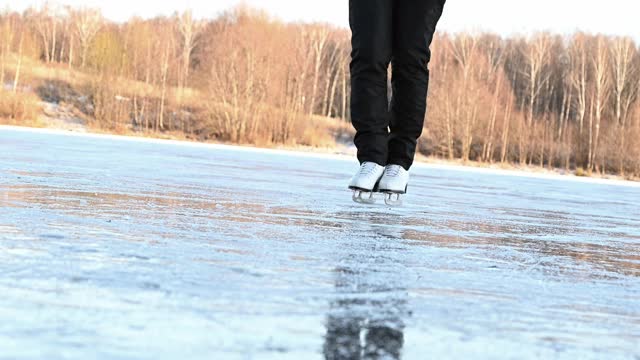 穿着白色花样滑冰鞋的女人在结冰的湖面上滑冰。冬季户外运动视频素材
