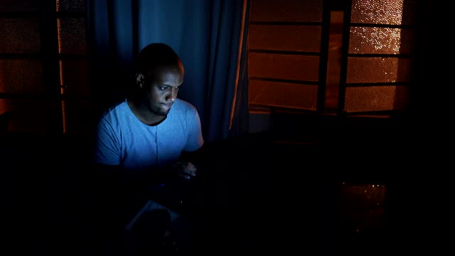 一名非洲男子在深夜漆黑中浏览互联网视频素材