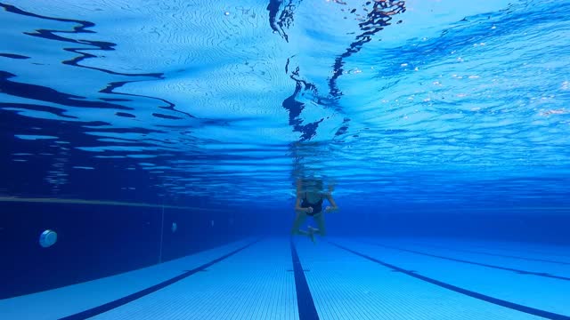 低角度观看亚洲华裔女游泳运动员游过游泳池视频下载