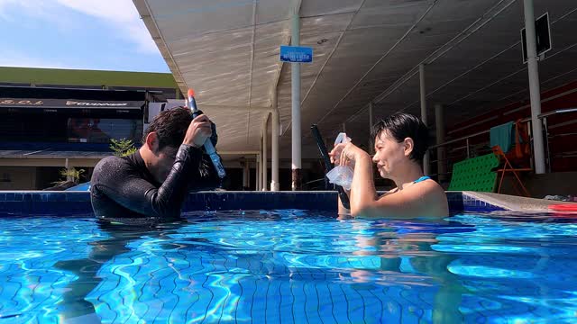 亚洲中国成熟的女人带着水肺面罩练习浮潜呼吸练习在水里和她的教练视频下载