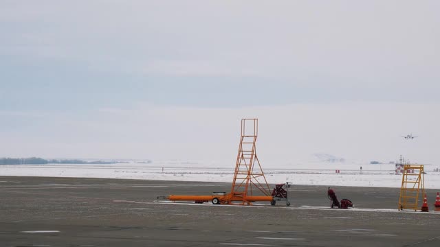 旅客飞机在多云的天空背景下降落到机场跑道。资料片。信号锥体，梯子在机场跑道上。视频下载