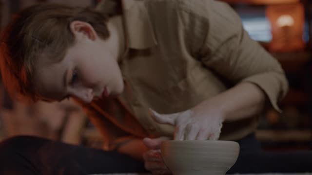 年轻的女陶工在她的陶艺工作室工作时，正在塑造一个形状视频素材
