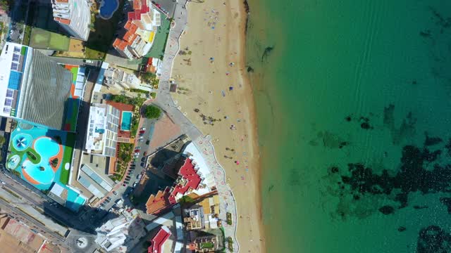 一架无人机在西班牙卡尔普市海滩上空的鸟瞰图。我们可以从上面的海滩上的游客和建筑4K视频素材