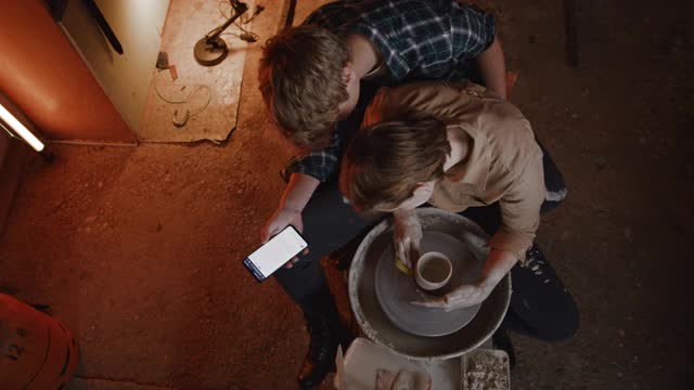 一对年轻夫妇在陶艺工作室用智能手机制作陶土视频下载