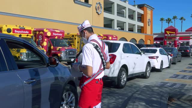 2019冠状病毒病大流行期间，in - n - out Burger汽车餐厅的销售人员戴着口罩为顾客服务，加利福尼亚州洛杉矶，4K视频素材