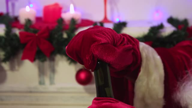 圣诞老人的手在红色手套打开香槟特写。视频下载