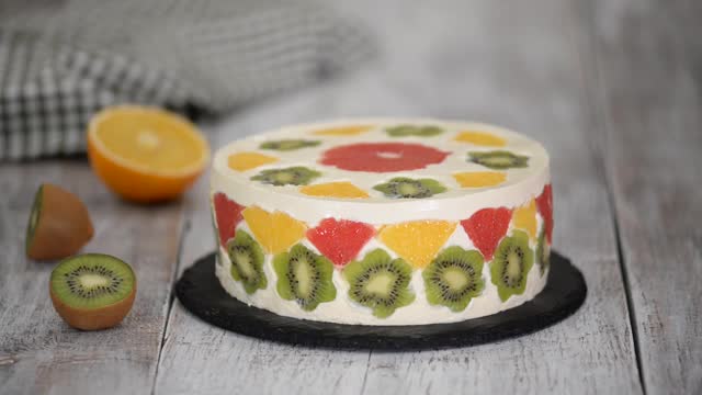 女人切一个美味的水果慕斯蛋糕。用新鲜水果和果冻装饰的蛋糕视频下载