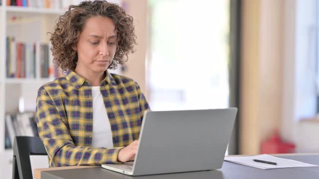疲惫的混血儿女性在工作时使用笔记本电脑导致背部疼痛视频素材