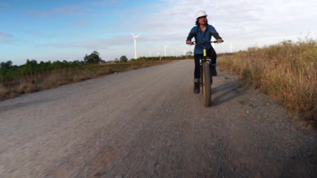 一位亚洲女工程师正骑着自行车检查风力涡轮机系统视频素材
