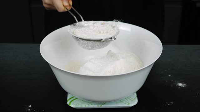 用手将面粉通过筛子倒入碗中。用面粉手工制作的生面团。披萨或烘焙用糕点的制作工艺视频素材