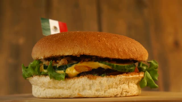 美味的汉堡上面有小的墨西哥国旗和牙签。美味的汉堡旋转。视频下载