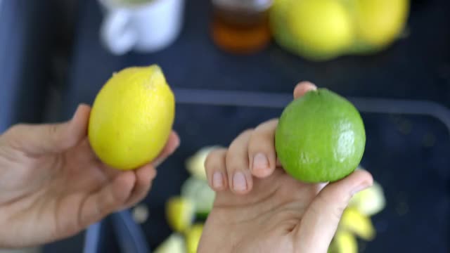 女性的手拿着一个柠檬和一个酸橙在水果片上视频素材