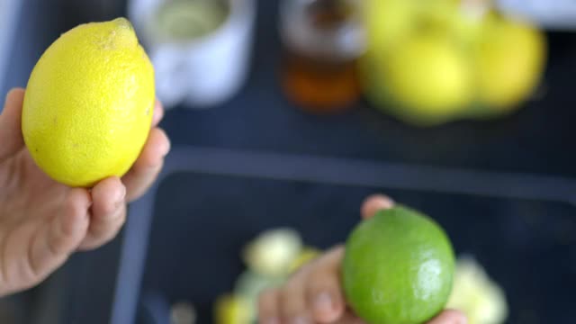 女性的手拿着一个柠檬和一个酸橙在水果片上视频素材