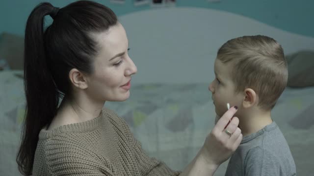 用棉签清洁耳朵的父母正在照顾她的孩子视频素材