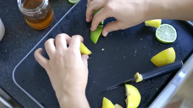 女性的手在黑色托盘上切柠檬和酸橙视频素材