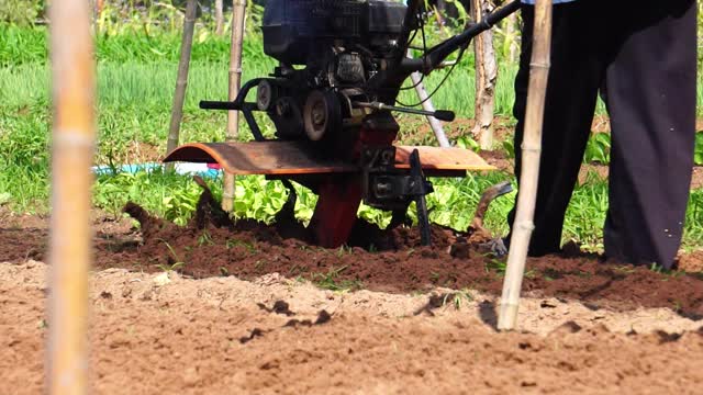 一位亚洲男性农民正在用机器耕田视频素材