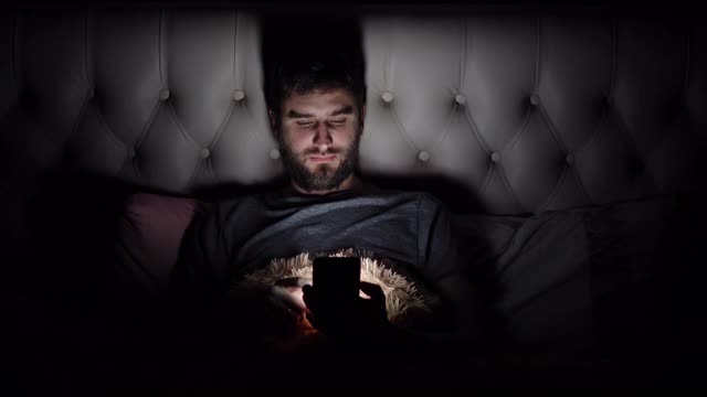 男人在睡前使用智能手机视频下载