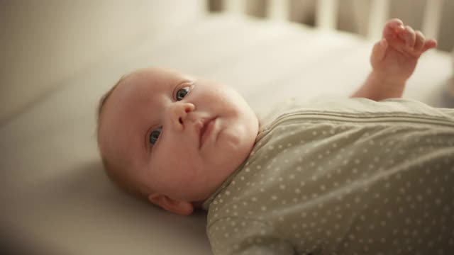 可爱的特写镜头一个可爱的新生儿躺在婴儿床上。在舒适的家空间一个高加索新生儿的顽皮肖像。童年、新生活和为人父母的概念。视频素材
