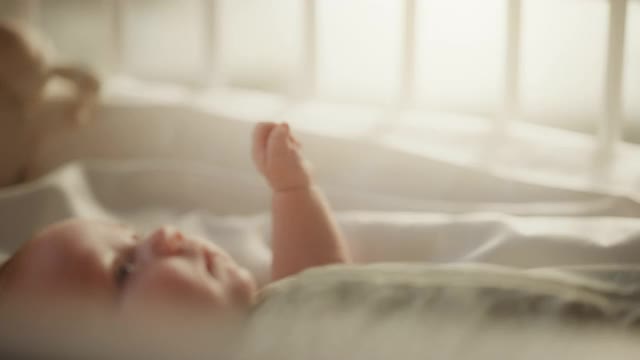 新生儿玩妈妈的手和手指，而躺在婴儿床上的特写镜头。白种人新生儿蹒跚学步与妈妈博宁。童年、新生活和为人父母的概念视频素材