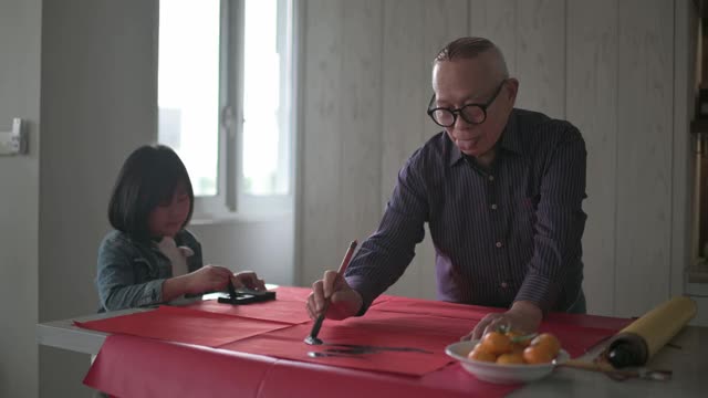 亚洲华裔年轻女孩帮助和学习她的祖父写中国书法视频素材