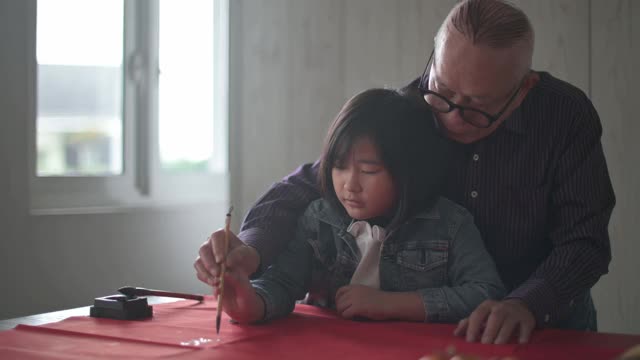 亚洲华人小女孩向她的祖父学习写中国书法视频购买