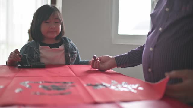 亚洲华裔年轻女孩帮助和学习她的祖父写中国书法视频素材
