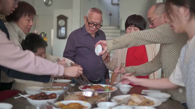 亚洲华人多代家庭庆祝中国新年前夕与传统食物娄桑(生鱼菜肴)团圆饭视频素材