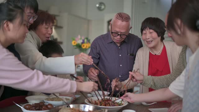 亚洲华人多代家庭庆祝中国新年前夕与传统食物娄桑(生鱼菜肴)团圆饭视频素材