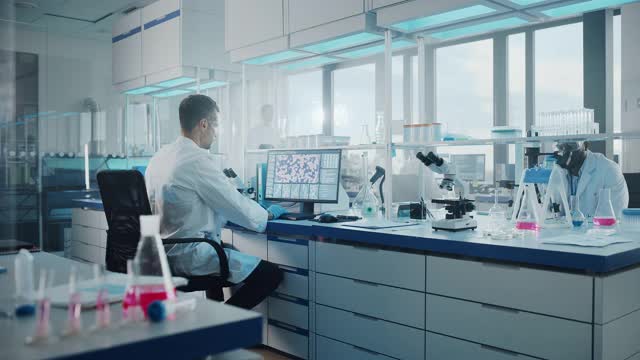 医学实验室，有多民族的生物技术科学家开发药物，微生物学家在计算机上工作，显示基因编辑界面。放大照片视频素材