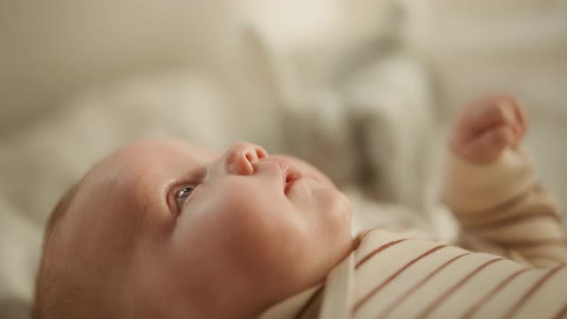 亲密的母亲给一个可爱的新生婴儿的奶嘴，而他是躺在婴儿床在舒适温暖的房间。母亲与新生儿的亲密关系。儿童与父母的概念。视频素材
