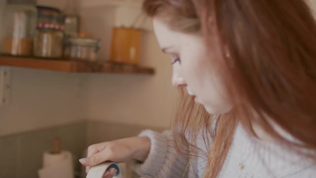 长红头发的女人微笑着在厨房泡茶视频下载