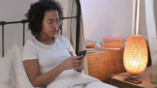 非洲女性在床上用智能手机聊天视频素材