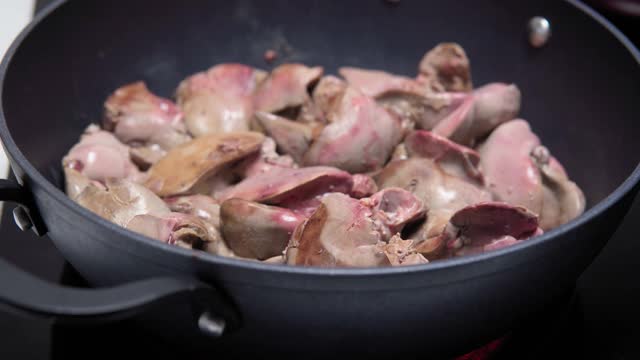 在家庭厨房的陶瓷炉上用平底锅煎鸡肝视频素材