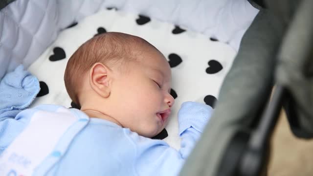 特写户外肖像的小男孩睡在甜蜜的婴儿车视频素材