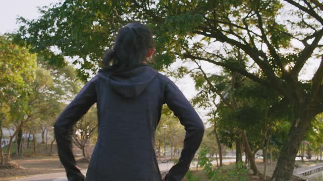 迷人的亚洲少女在公园里跑步。年轻女子晨跑锻炼。视频素材