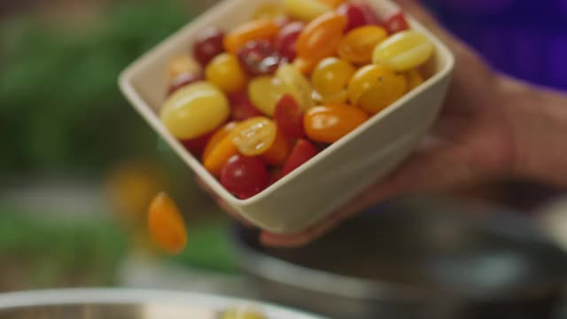 SLO MO CU主厨将五颜六色的西红柿倒在什锦蔬菜上视频下载