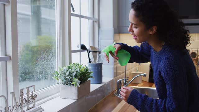 混血女人在厨房里给植物浇水视频素材