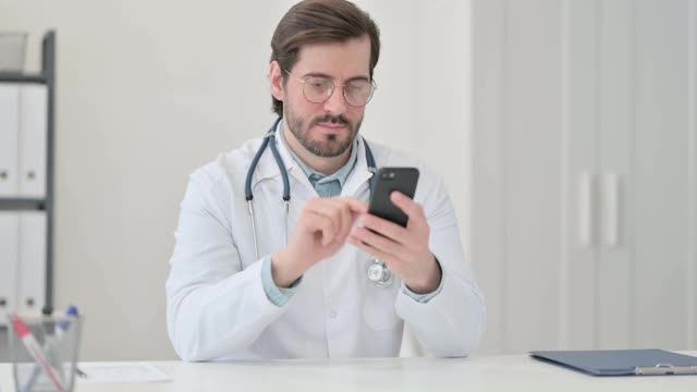 年轻男医生在工作中使用智能手机聊天视频素材