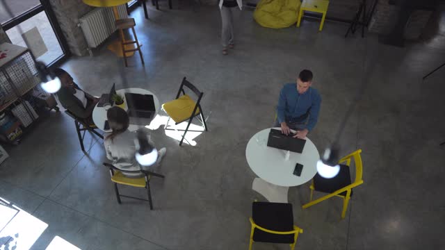 男同事坐在桌边，另一名女同事走近他并向他展示文件视频素材