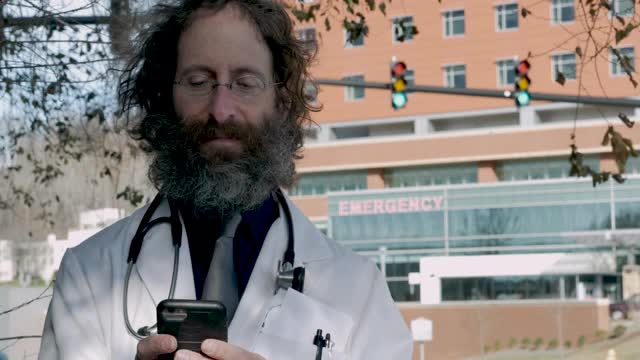 男医生在急救室医院外使用智能手机视频下载