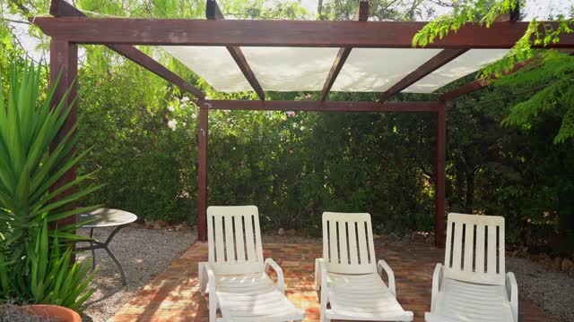 一个织物的天篷，从太阳在一个凉爽，凉爽，豪华的地点在花园里。酒店里有休闲椅。视频下载