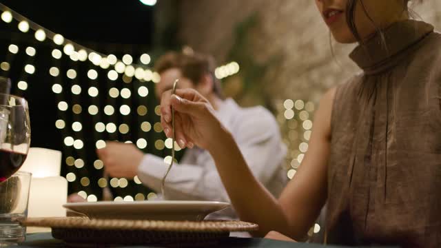 在浪漫的美食晚餐或午餐中，女人用叉子吃东西时，手的细节。广角镜头。朋友们在翁布里亚的意大利之旅，4k慢镜头视频素材