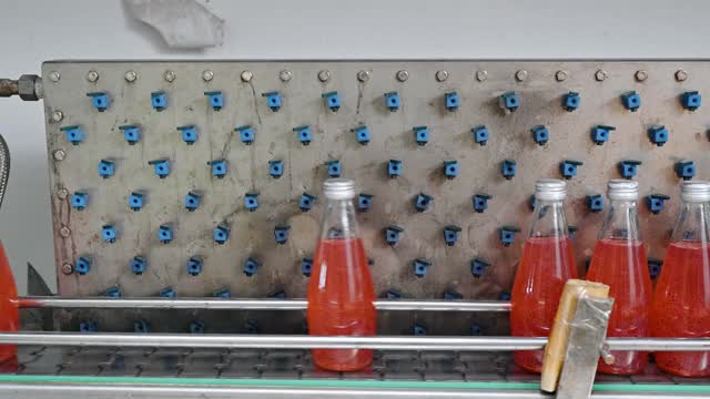 灌装厂自动生产线上的红果汁瓶滑动视频素材