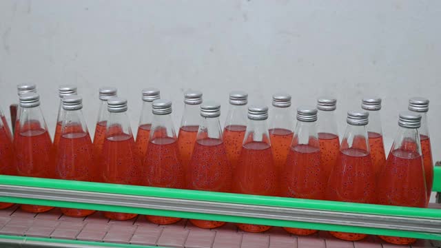 灌装厂自动生产线上的红果汁瓶滑动视频素材