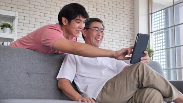 亚洲人的儿子和爸爸在社交媒体上玩得很开心。视频素材