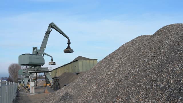 挖掘机的工作是将鹅卵石从石块堆中搬运到集装箱中。视频素材