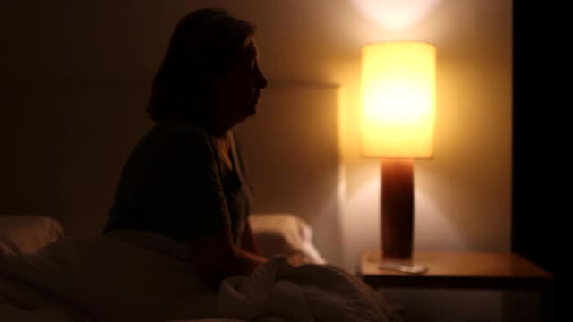 焦急的女人坐在床边无法入睡。夜不能寐的人在担心视频素材